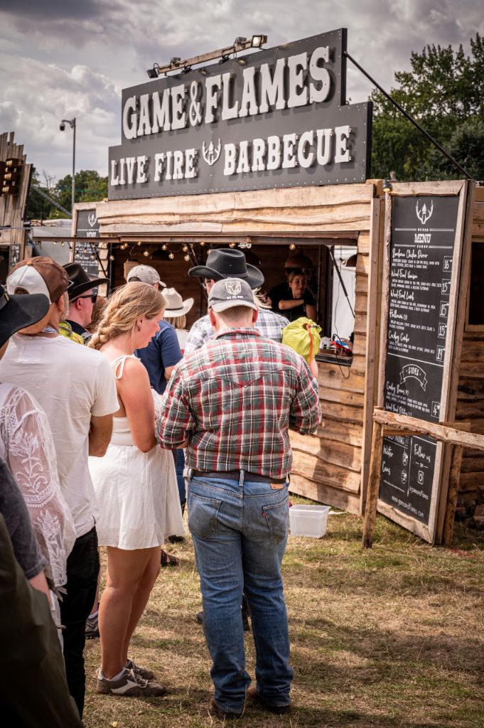 Customers queuing at Game and Flames festival stand with menu board